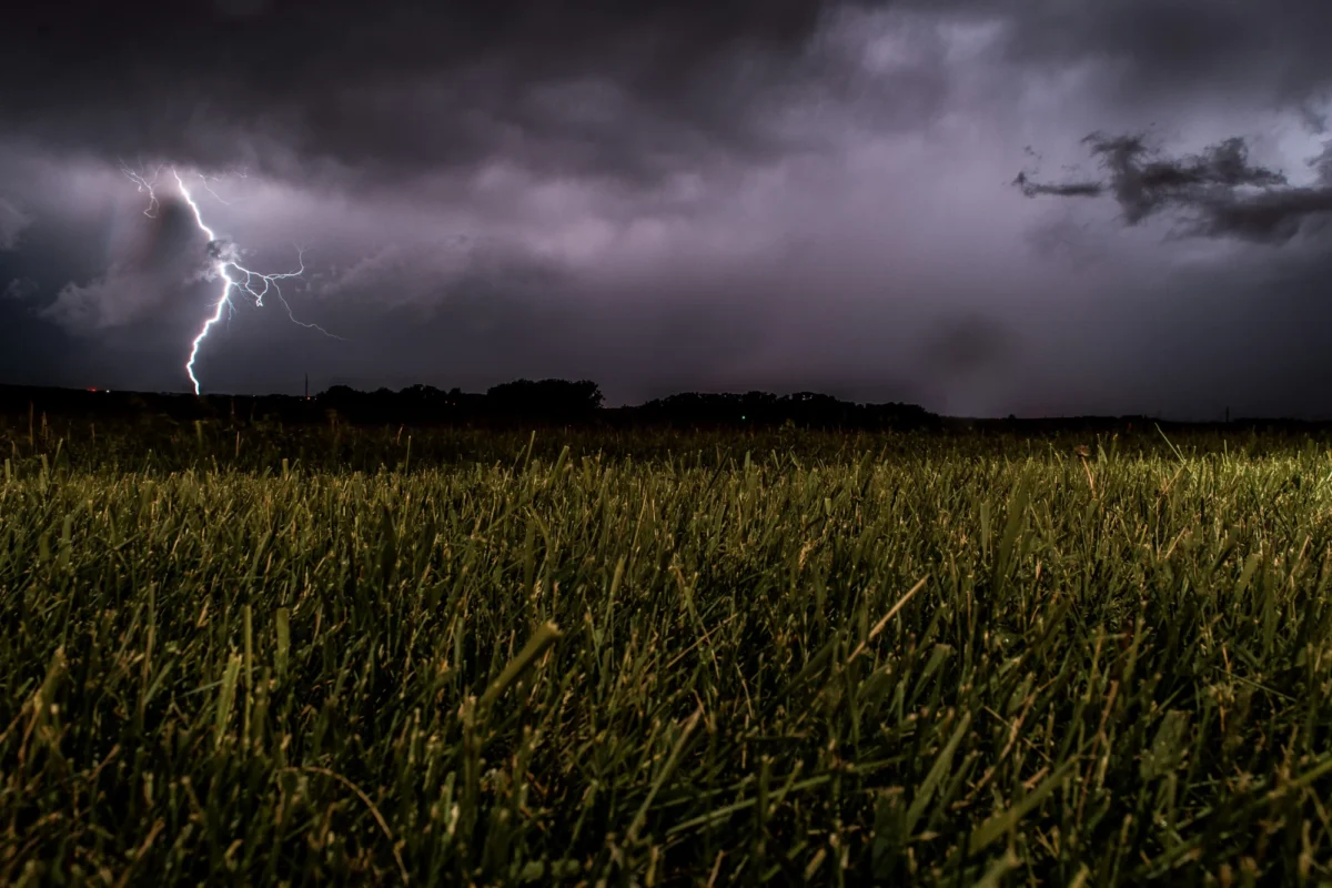 Thunderstorm with dark clouds and lightning moving across field